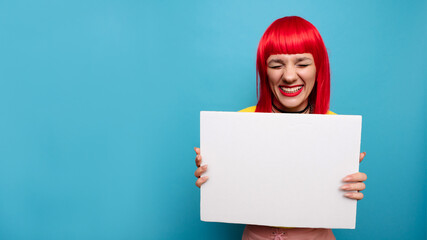 Photo of a young woman. A happy positive girl is holding a poster or banner for an advertising promo with a clean and empty space