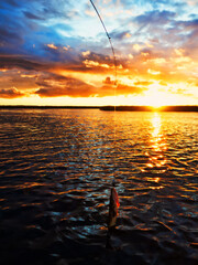 Fishing at sunset. Catching predatory fish on spinning. Sunset colors on the water surface, sunny...