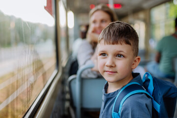 Close-up of little boy travelling to school by bus in the morning, commuting and sustainable...