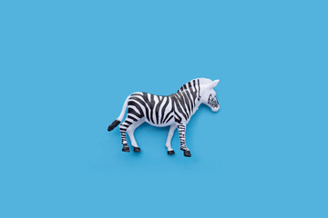 Fototapeta na wymiar Plastic zebra toy on blue background.