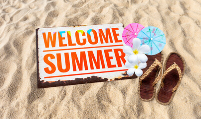 Welcom summer sign on sandy beach with jute slipper and flower with paper umbrella