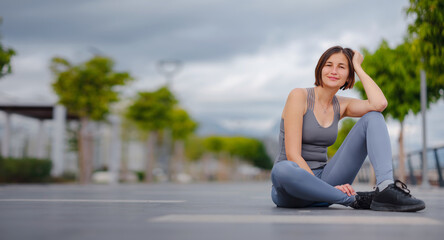 Fototapeta na wymiar outdoor sports, workout and wellness concept. asian young strong, confident woman in sportive clothes Relaxing After Fitness Workout In Park. Female runner taking break from running sport.