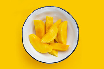 Yellow mango slices on yellow background.