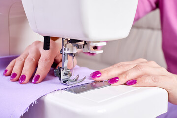 Woman sewing a dress on a sewing machine. Close-up, selective focus