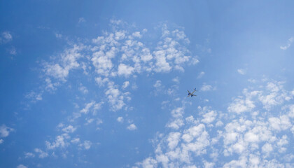 The plane is flying in a blue sky among clouds and sunlight, a copy of space