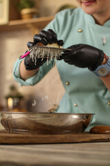 Female chef prepares Italian pasta with tomatoes and permesan in a bright kitchen in a rustic style. Mint coat apron. Chef at home