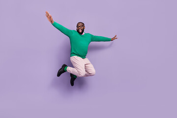 Fototapeta na wymiar Full length photo of good mood overjoyed young man feel childish jumping up flying isolated on violet color background