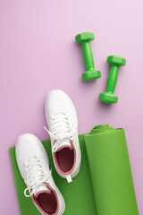 Sports concept. Top view vertical photo of white footwear over green exercise mat and dumbbells on isolated pastel violet background