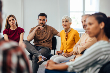 Focused people, carefully listening to their therapist, talking to each other.