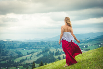Woman in red at the green fields of Mountains