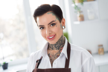 Portrait of young adorable lady with piercing and tattoo working as chef in restaurant make...