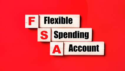 On a bright red background, wooden cubes and blocks with the text FSA Flexible Spending Account. Manufacturing of wooden toys.