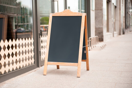 Blank wooden sandwich board near cafe outdoors. Mockup for design