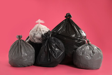 Trash bags full of garbage on pink background
