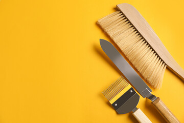Beekeeping tools on yellow background, flat lay. Space for text