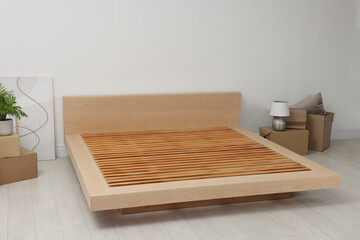 New wooden bed frame, moving boxes and decor elements indoors