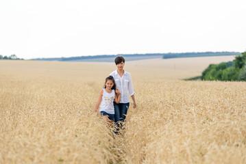 Naklejka na ściany i meble World food crisis. Deficit of grain in the world markets. Mom and daughter are walking in a wheat field.