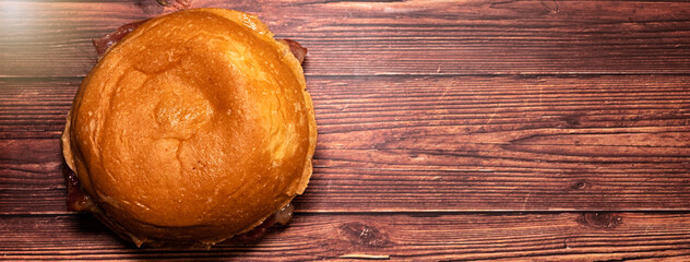 Top view of a hamburger on a dark wood table. Beef burger. Horizontal banner with space for text.