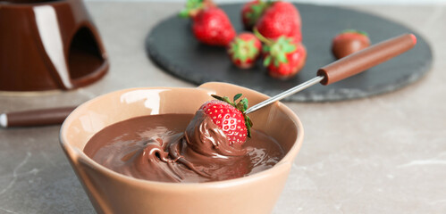 Tasty strawberry dipped into chocolate fondue on table, closeup. Banner design