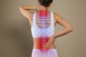 Woman suffering from pain in back on beige background, closeup