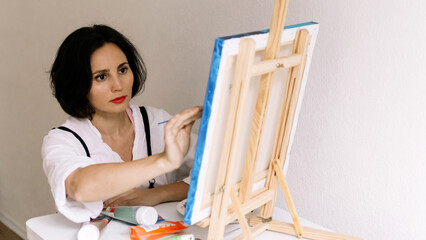 Innovative real female painter using palette knife on big canvas. Modern artwork paint on canvas, creative, contemporary and successful fine art artist drawing portrait