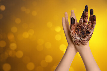 Woman with henna tattoo on palm against blurred lights, bokeh effect. Space for text