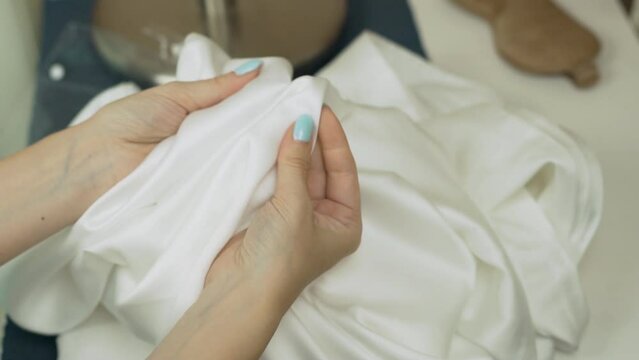 Girl Checks Quality of Fabric Silk Satin Tencel Bamboo, Tests Bed Linen, Quality of Seams. Close-up of Hands and Silky White Material.
