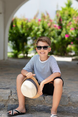 Vertical outside portrait of handsome summer kid at sunny day. Happy smiling schoolboy in striped...