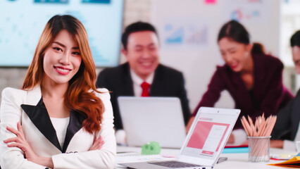 Confident young businesswoman sitting smiling at the camera in a meeting room.