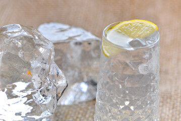 transparent alcoholic cocktail with ice, decorated with a slice of lemon, macro photo