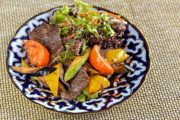 warm salad with veal on a patterned plate
