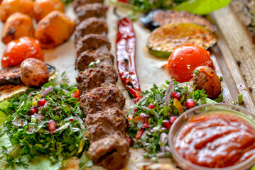 oriental dish, a huge one-meter kebab on a board with grilled vegetables, salad and lavash, macro photo