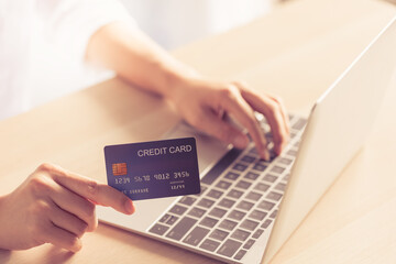 closeup woman hand holding credit card on hand and typing code on laptop