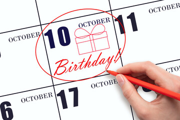 The hand circles the date on the calendar 10 October, draws a gift box and writes the text Birthday. Holiday.