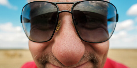 Man with distorted face wearing big sunglasses looking to camera closeup
