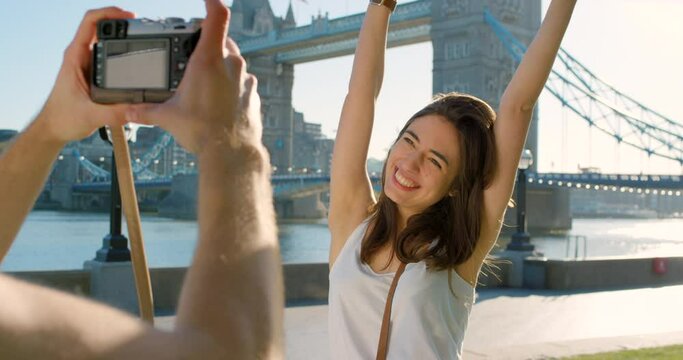 A man taking a photo on his camera of his carefree girlfriend on holiday