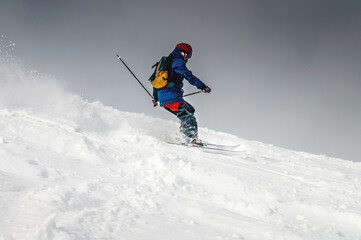Fototapeta na wymiar Freeride, a man is stylishly skiing on a snowy slope with snow dust plume behind him