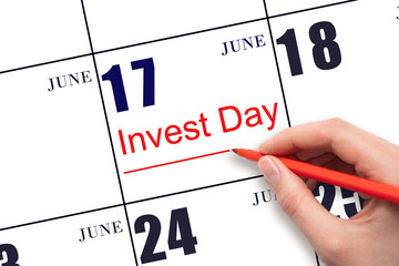 Hand drawing red line and writing the text Invest Day on calendar date June 17. Business and financial concept.