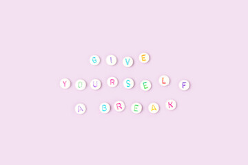 Give yourself a break. Quote made of white round beads with colorful letters on a purple...