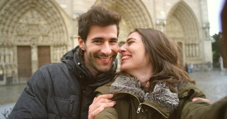 A couple in love kissing and taking a selfie in front of Notre Dame - Powered by Adobe