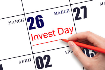 Hand drawing red line and writing the text Invest Day on calendar date March 26. Business and financial concept.