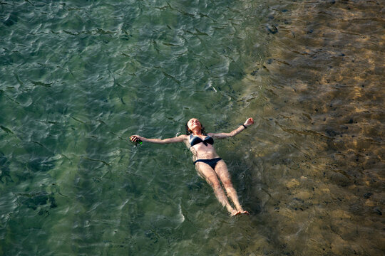top view of woman floating in the sea near sandy beach