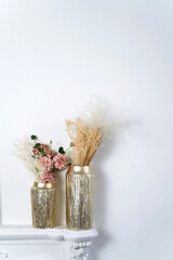 Stylish elegant eco composition of living room with white false fireplace, dried flowers plants pampas grass.