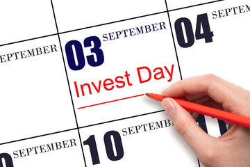 Hand drawing red line and writing the text Invest Day on calendar date September 3. Business and financial concept.