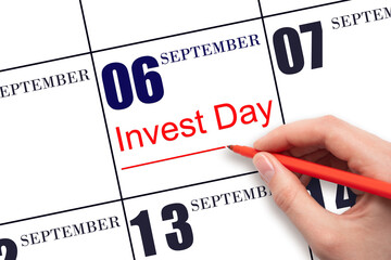 Hand drawing red line and writing the text Invest Day on calendar date September 6. Business and financial concept.