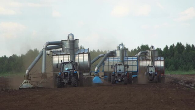 Peat harvester agricultural tractors on collecting extracting peat at sunset. Mining peatland.