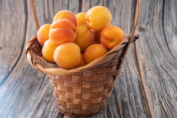 fresh ripe apricots in a basket on a wooden table