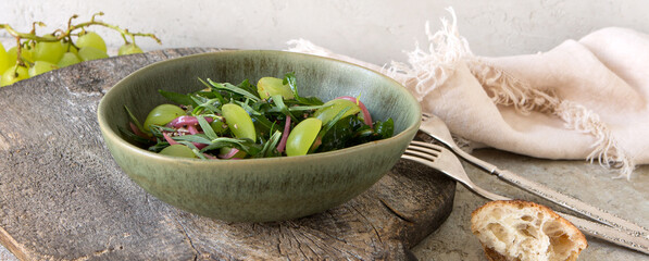 bowl with salad with grapes, tarragon and red onion on the table