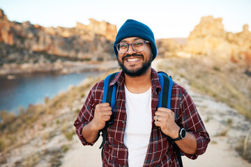 An attractive hiker smiles with backpack in the mountains at sunset