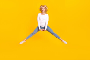 Full body photo of sweet millennial blond lady jump wear shirt jeans footwear isolated on yellow background